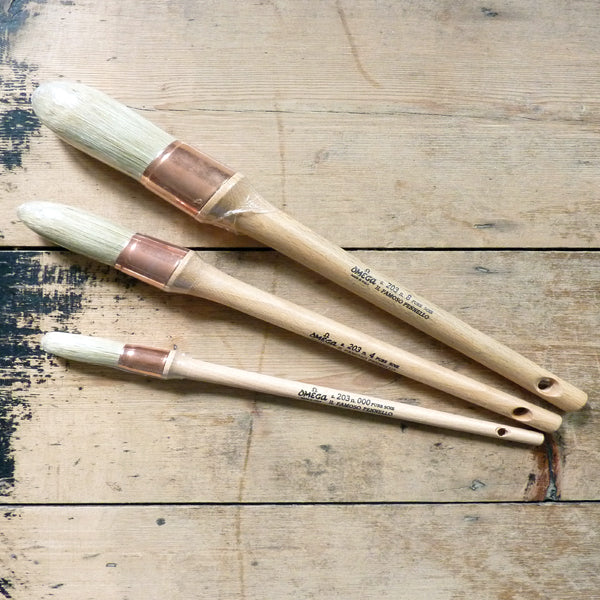 The Omega 203 Sash Brush features white hog bristles, a copper ferrule, and a long, untreated wood handle, making it uniquely suited to larger painting projects.